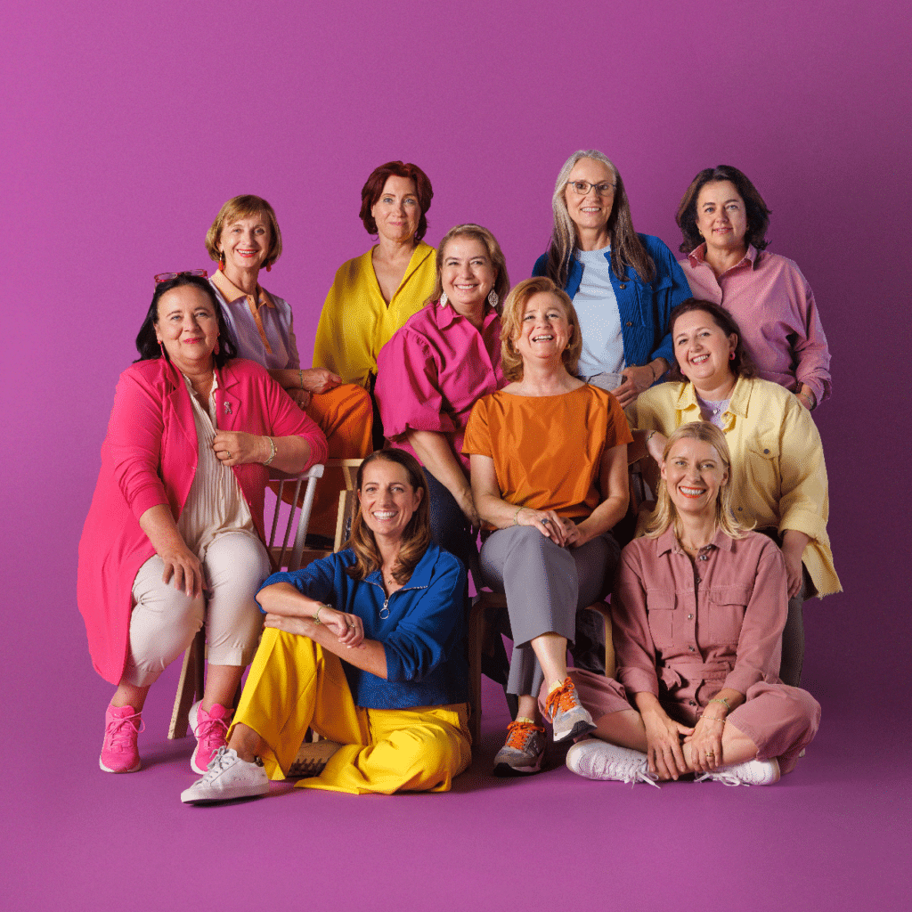 10 Frauen stehen als Gruppe vor einen lila Hintergrund