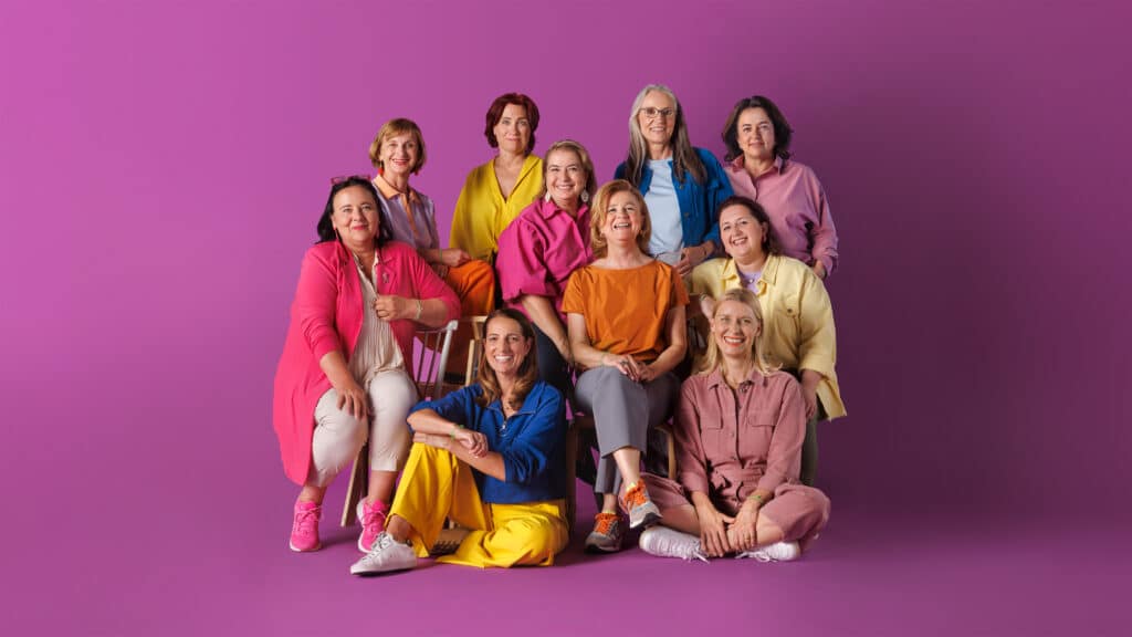 Zehn Frauen unterschiedlichen Alters vor pink-violettem Hintergrund